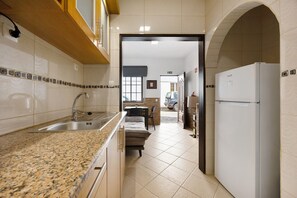 Una cocina con encimera de granito, pileta de acero inoxidable y refrigerador blanco.