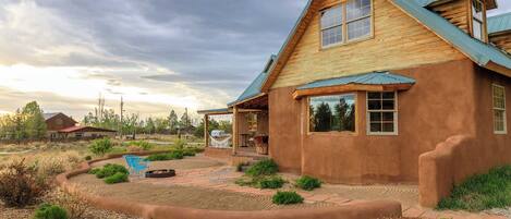 A wooden house with a sloped roof, a covered porch, and a fire pit in the yard.