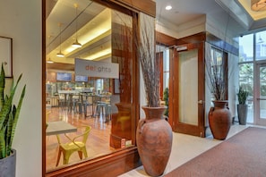 Ein modernes Interieur mit einer Rezeption, großen Vasen und einem durch Glastüren einsehbarer Essbereich.