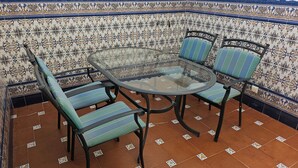 Een glazen ronde tafel met vier gestreepte stoelen, omgeven door betegelde vloertegels.