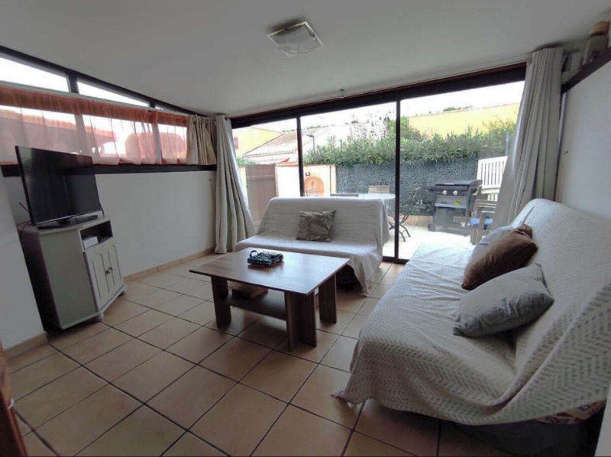 Une pièce comprenant un lit, un canapé, une table basse, un téléviseur et une porte-fenêtre coulissante donnant sur un espace extérieur.