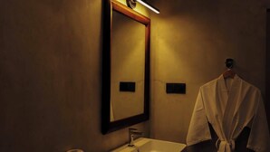 A bathroom with a mirror, sink, and robe hanging on the wall. - Crystal Green Beach Villa – Villa 3 (Kuligoda)