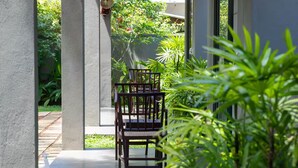 A covered outdoor seating area with chairs and tables, surrounded by greenery. - Crystal Green Beach Villa – Villa 3 (Kuligoda)