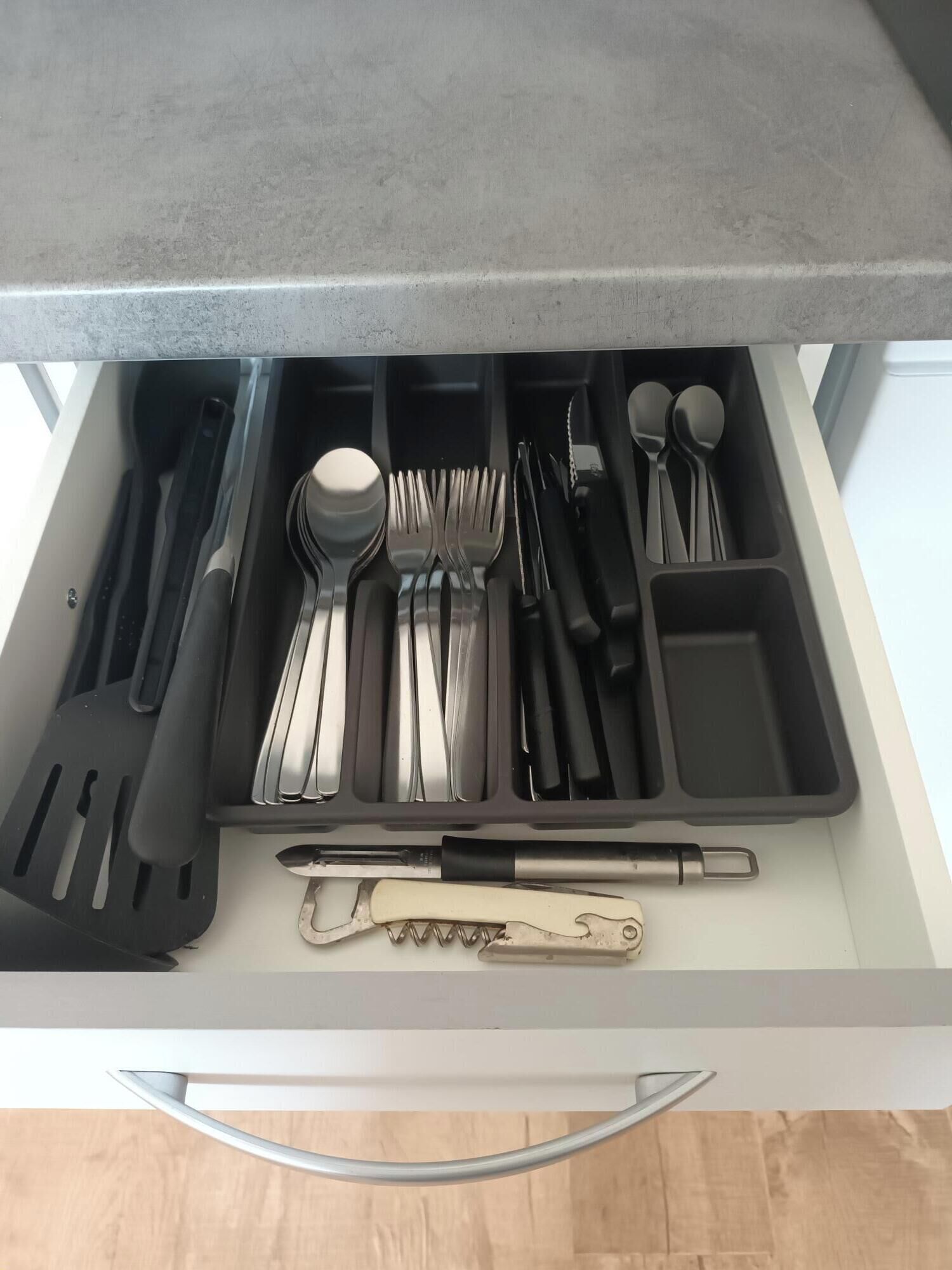A kitchen drawer with utensils and a spatula.