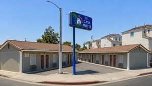 A motel with a sign indicating 'MI CASA MOTEL,' featuring a house and palm tree logo.