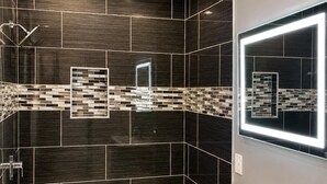 A modern bathroom with a bathtub, vanity, and a mirror with integrated lighting.