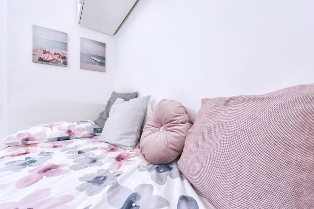 A bedroom with a bed, pillows, and two wall-mounted pictures.