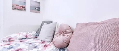 A bedroom with a bed, pillows, and two wall-mounted pictures.