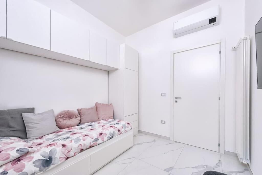 A bedroom with a bed, pillows, a wardrobe, a door, and an air conditioning unit.