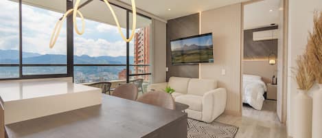 A modern living room with a large window, a sofa, a coffee table, and a dining area.