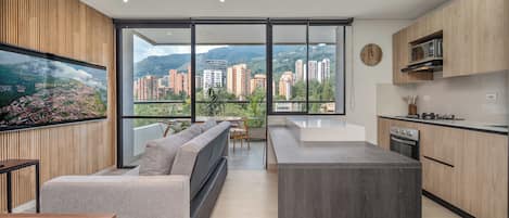 Eine moderne Küche mit einer großen Kochinsel, einem Essbereich inklusive Sofa und Blick auf eine Stadtlandschaft durch große Fenster.