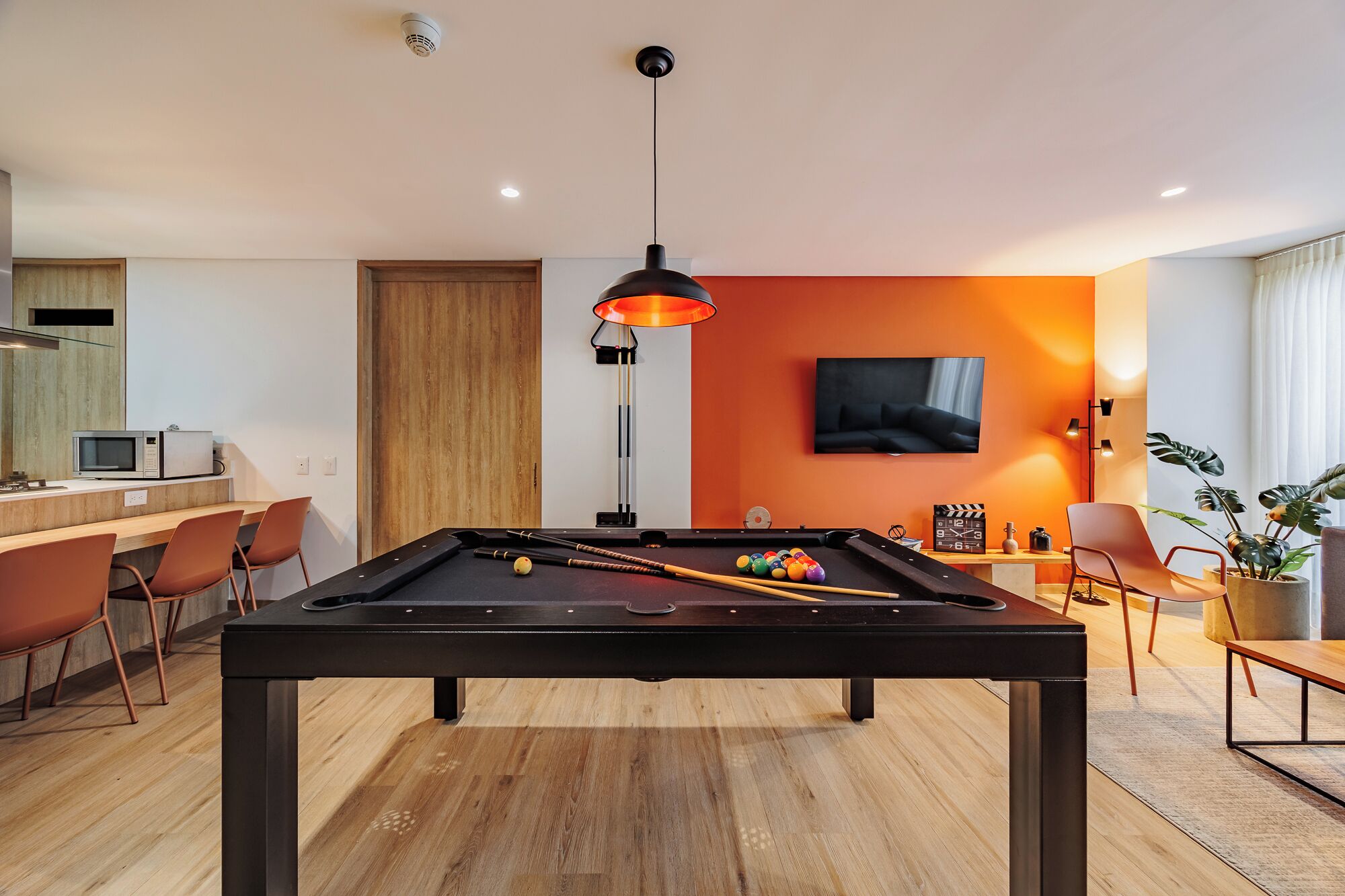 A modern living room with a pool table, a television, and a dining area.
