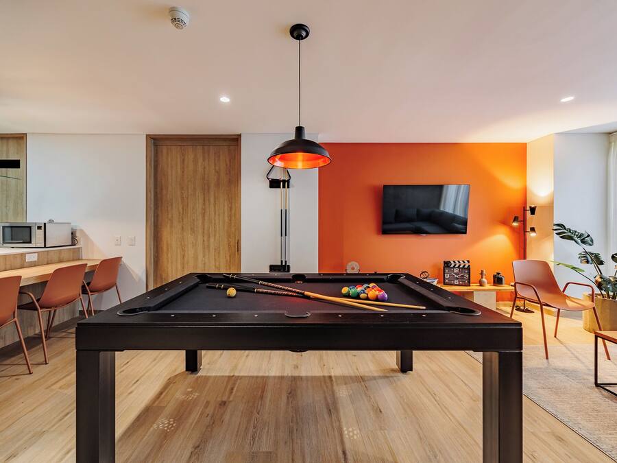 A modern living room with a pool table, a television, and a dining area.