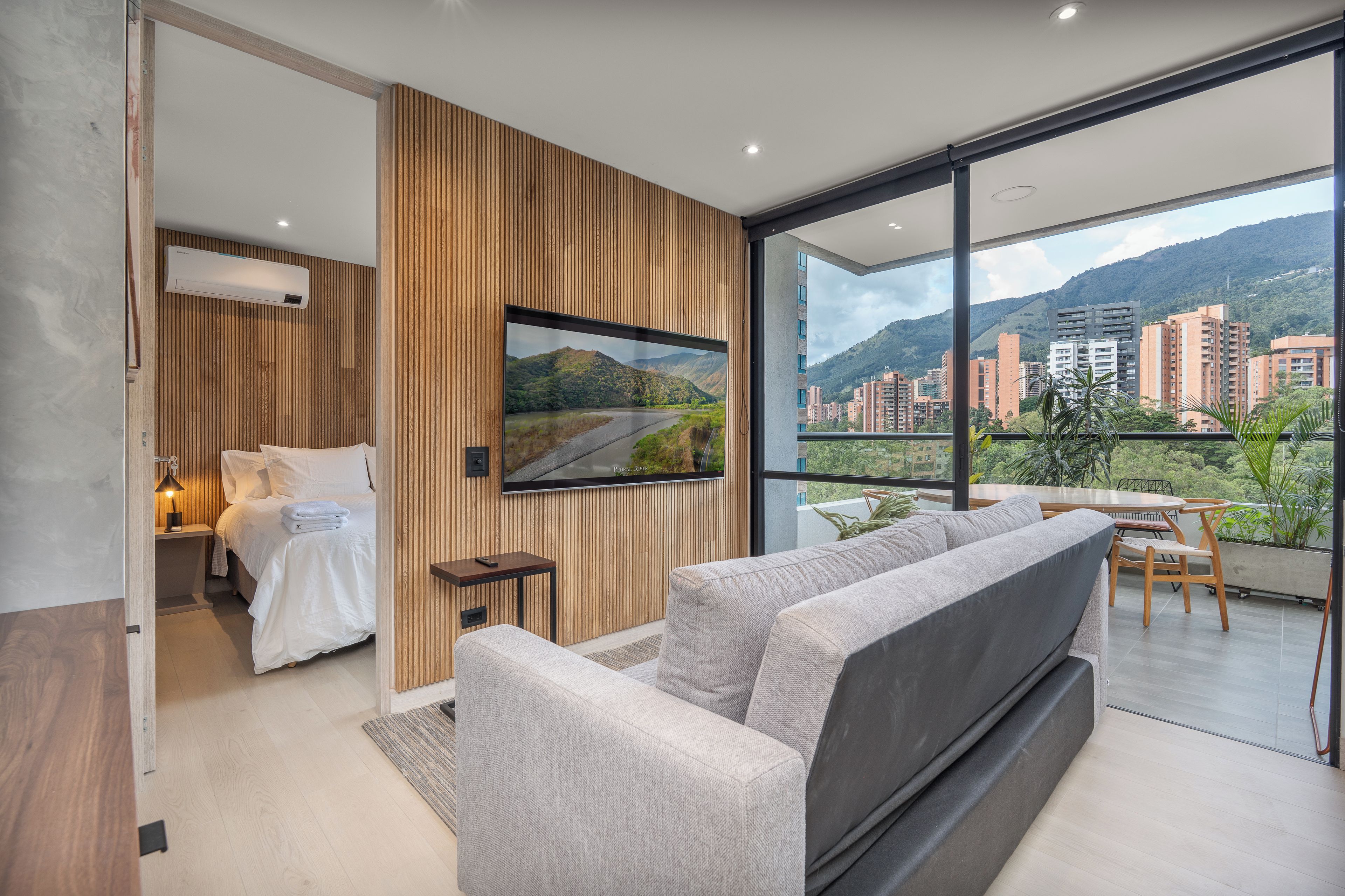 A modern bedroom with a bed, bedside table, and a mounted TV.