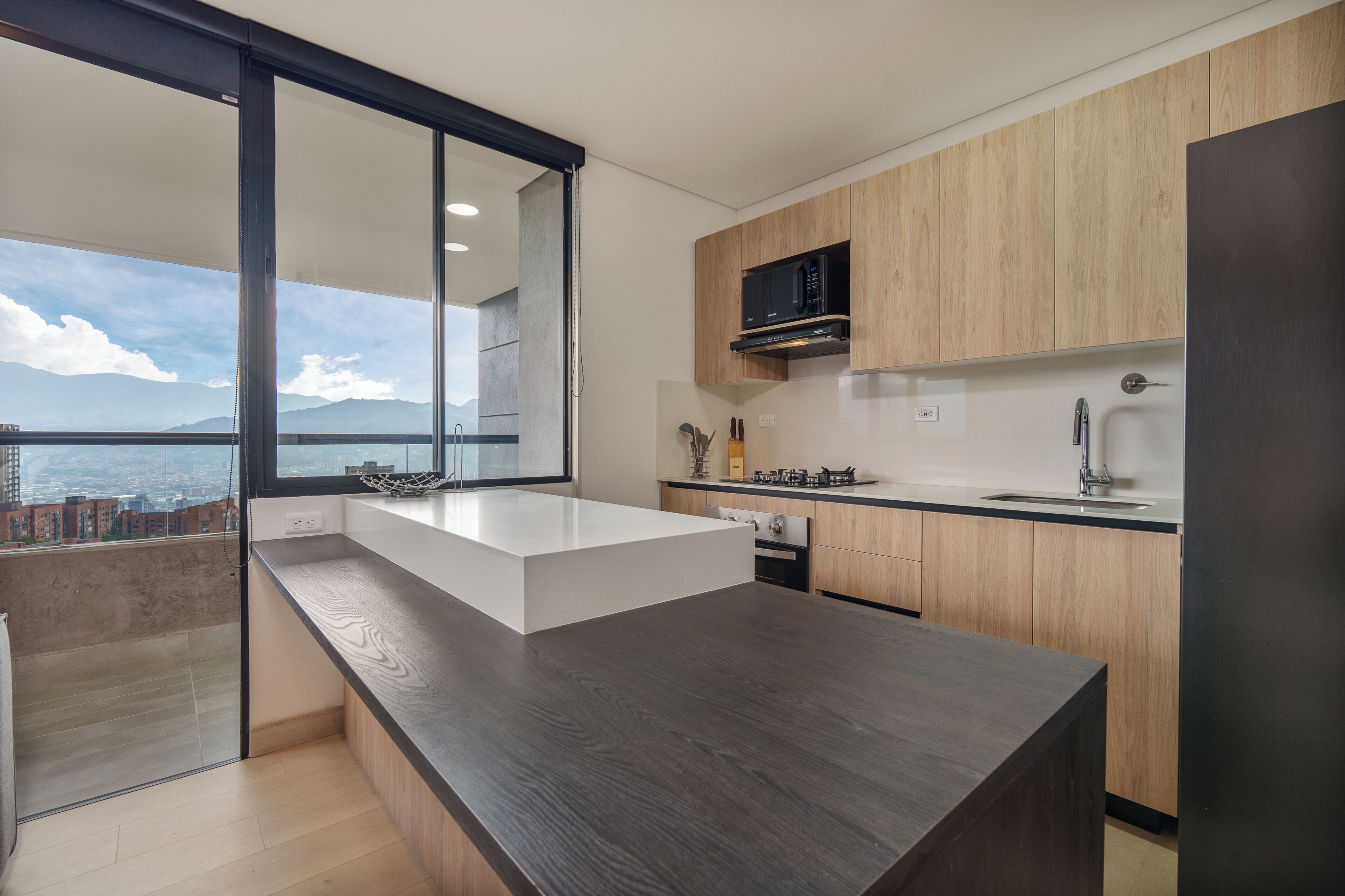 Una cucina moderna con un'isola grande, mobili in legno e vista sulla città.