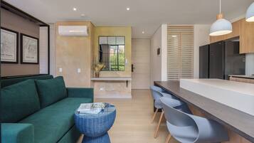 Een moderne keuken met een houten aanrecht, een zwarte koelkast, en een eethoek met een witte tafel en grijze stoelen.