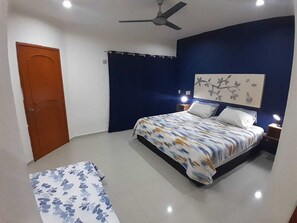 Ein Schlafzimmer mit Bett, Deckenventilator, Nachttisch und Tür.