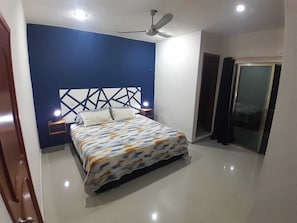 Ein Schlafzimmer mit einem Bett, Deckenventilator und Nachttisch.