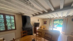 Un comedor con una mesa redonda, sillas, chimenea, televisor y vistas a una piscina.