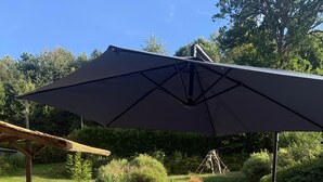 Zona de piscina con mesa lista para comer, rodeada de sillones de descanso y un espacio de estar cubierto.