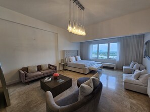 A spacious living area with a large bed, a sofa, a coffee table, and a view of the city. - Sunset Loft Oasis/ Bright & Airy/ One hotel Living (Miami Beach)