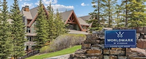 A large, multi-story building with a stone facade and a prominent sign for Canmore-Banff Resort. - Spacious 1-bedroom condo with AC in enchanting Canmore (Canmore)