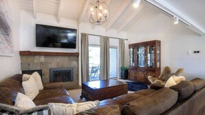 Una sala de estar con chimenea, sofás de cuero, un mueble de madera y un televisor montado.