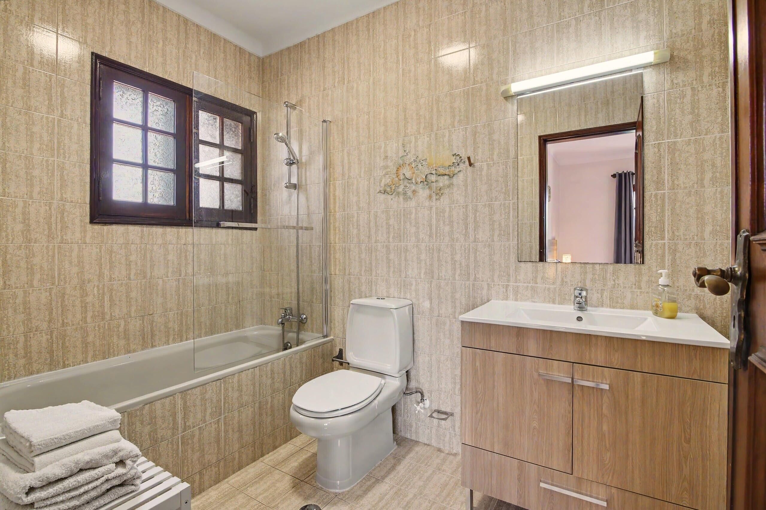 A bathroom with a bathtub, toilet, sink, and a mirror.