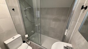 A modern bathroom with a glass-enclosed shower, a white toilet, and a sink with a chrome faucet. - Walk to Train Bolton ~Free Parking ~close to Shops (Farnworth)