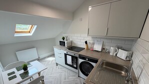 A compact kitchen with a washing machine, microwave, and sink. - Walk to Train Bolton ~Free Parking ~close to Shops (Farnworth)