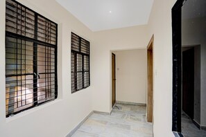 A hallway with two windows featuring metal bars, a tiled floor, and a door leading to another room.
