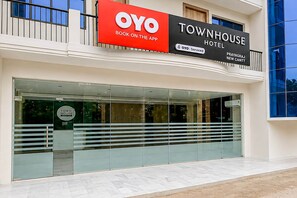 A Townhouse Hotel with a glass facade, a sign indicating OYO service, and a modern architectural design.