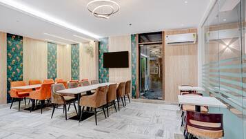 A conference room with a long table and chairs, a flat-screen TV, and an air conditioning unit.
