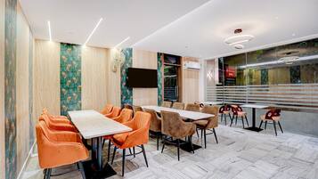 A conference room with a long table, multiple chairs, a flat-screen TV, and an air conditioning unit.