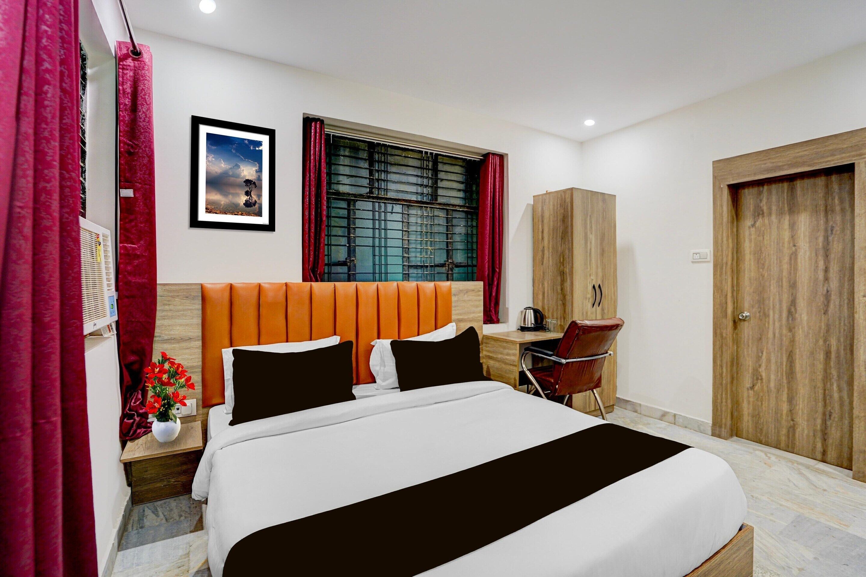 Habitación de hotel con cama, escritorio, silla, armario y ventana con cortinas.