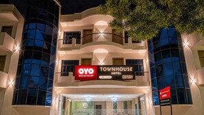 Ein mehrstöckiges Gebäude mit einem Schild für 'OYO Townhouse Hotel' und der Aufforderung 'BUCHEN IN DER APP'.