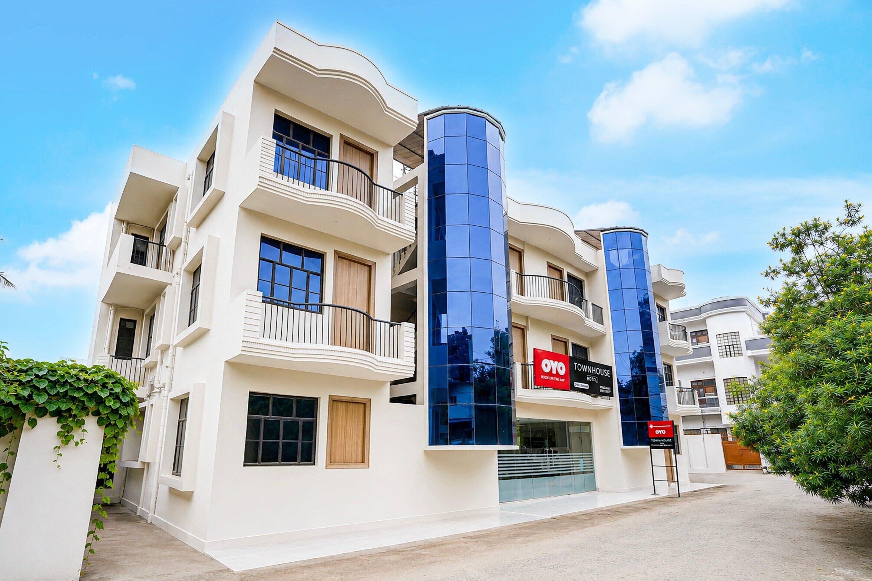 Un edificio de varios pisos con balcones, una fachada comercial y un cartel que dice 'OYO TOURNHOUSE'.
