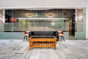 A modern interior with a black leather sofa, wooden coffee table, and glass partitions.