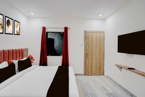Una habitación de hotel moderna con una cama, un televisor, una puerta de madera y una ventana con cortinas rojas.