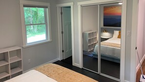 A bedroom with a bed, a window, a closet with sliding doors, and a painting on the wall. - A 3-bedroom mountain retreat perfect for families, friends, and every adventure! (Zirconia)