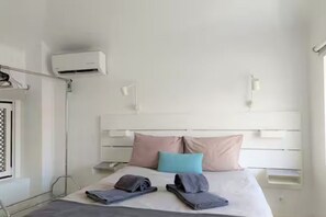 Ein Hotelzimmer mit Bett, Kissen, Nachttisch, Klimaanlage und Fenster.