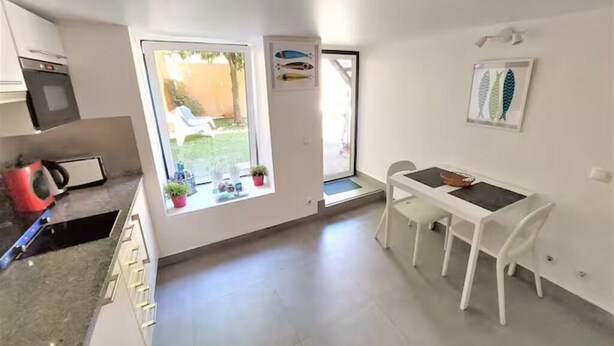 Una cocina moderna con horno integrado, un comedor con mesa y sillas, y un ventanal con vistas al exterior.