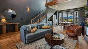 A modern living room with a sofa, coffee table, and a chair. There is a staircase leading to an upper level.