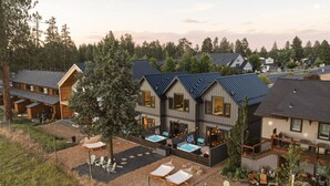 A modern multi-story building with a rooftop pool, outdoor seating, and a well-maintained garden.