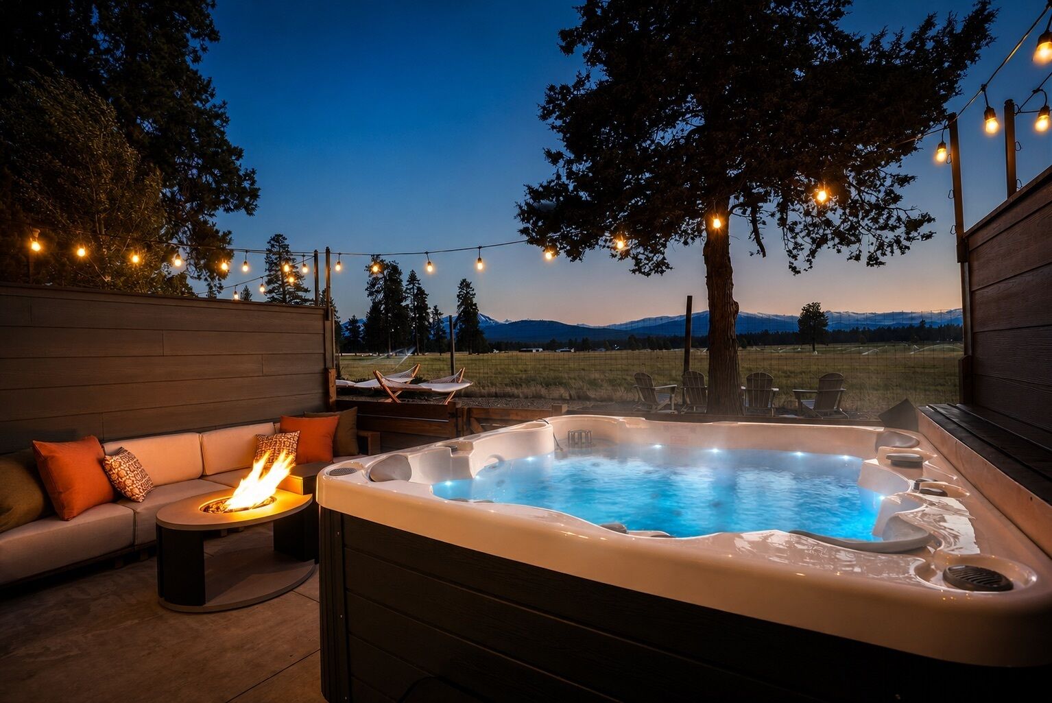 A hot tub with a fire feature, surrounded by a wooden deck and outdoor furniture.