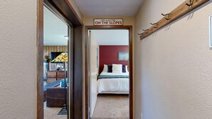 Un pasillo que conduce a un dormitorio con una cama, un televisor y un cartel sobre la puerta.