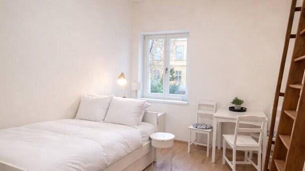 Une chambre à coucher avec un lit, un bureau, une chaise, un petit tapis et une fenêtre.