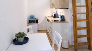 Une cuisine de taille réduite avec une table blanche, des chaises et une échelle en bois.