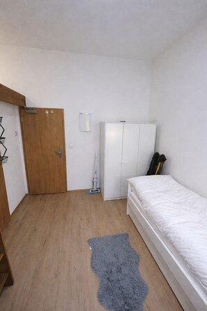A bedroom with a wooden door, a white wardrobe, a bed with a white mattress, and a grey rug. - Cozy Loft Space by Rentez (Prague)