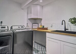A kitchen with a sink, a stove, and a laundry area.